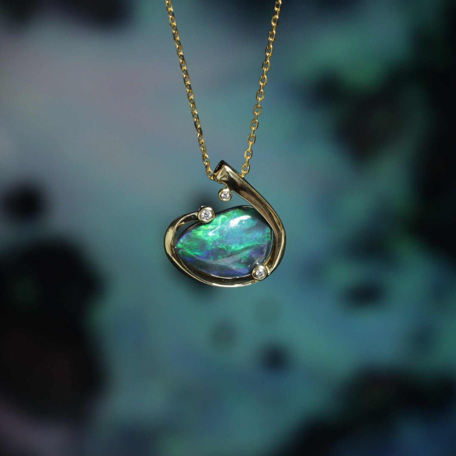 Solid Australian Black Opal pendant in 18K yellow gold with three bezel-set diamonds — angled view